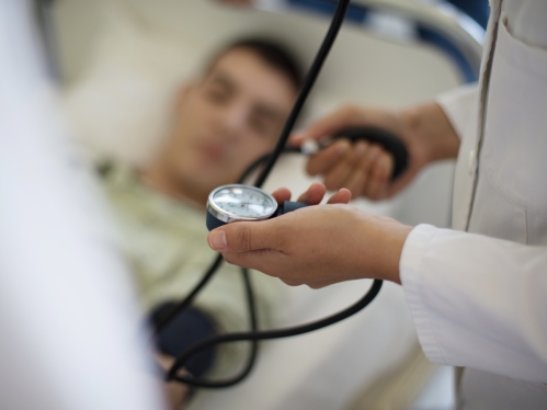 A doctor takes blood pressure of a patient lying in a hospital bed