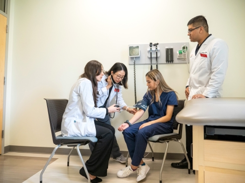 Pharmacy students take patient vitals in a simulation exam room
