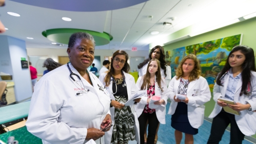 A faculty member provides instruction to medical students in a clinical space