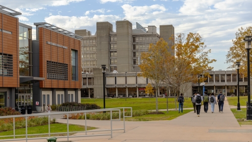 Students walk on a sidewalk on Busch Campus toward RWJMS research tower