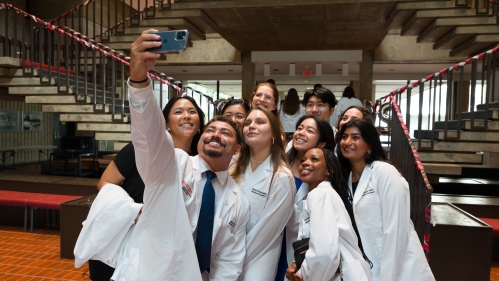 A group of students in white coats take a selfie after the White Coat Ceremony