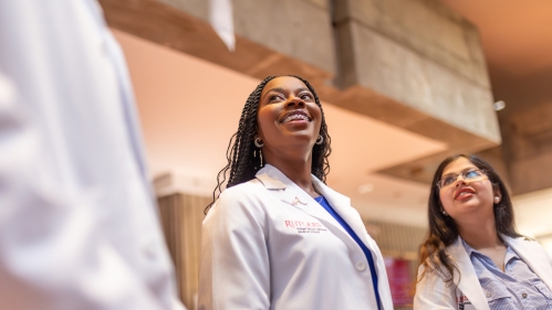 Medical students in white coats talk in the medical school