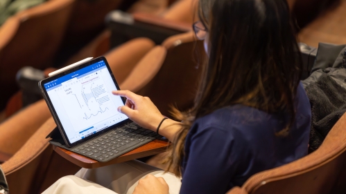 A student works on a laptop in a lecture hall