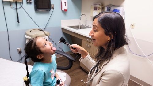 A doctor looks in a child's mouth in the clinic