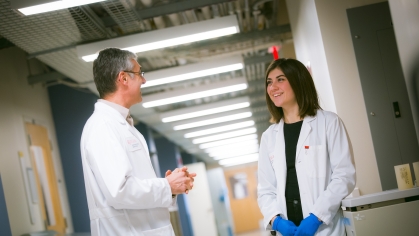 A student and researcher talk in a hallway