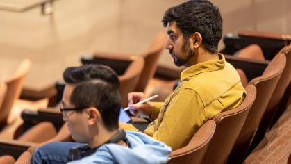 Two students listen to the professor in a lecture hall