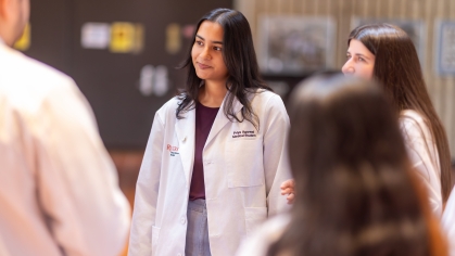 A group of students in white coats talk in the medical school