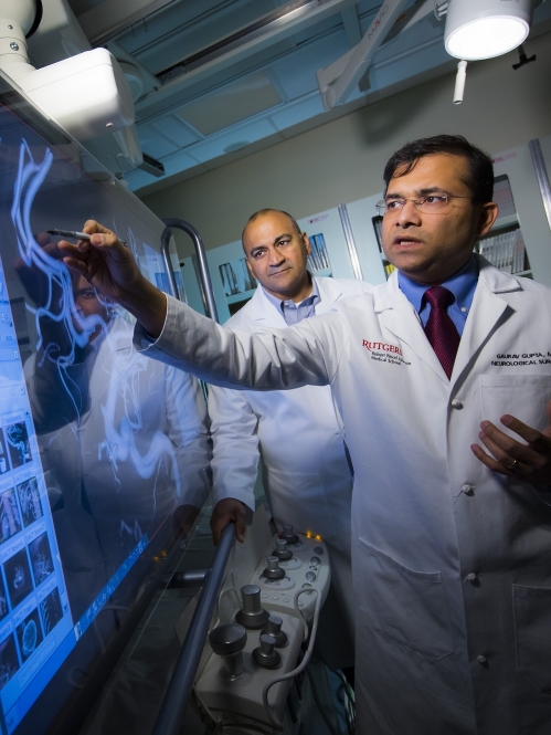 Neurological surgeons look at scans on a large screen in the OR