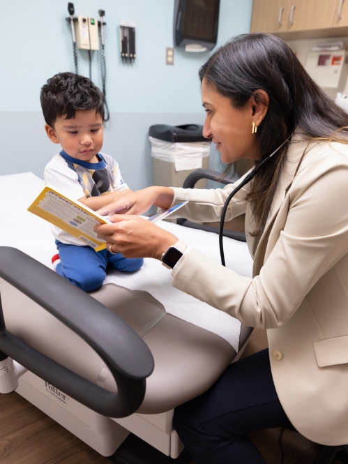 A doctor reads a book to a young patient in the clinic