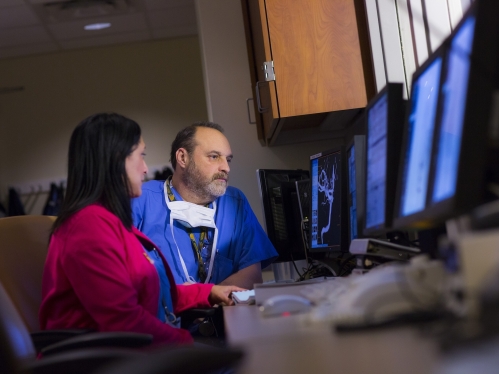 Two care team members look at screens in the angiography suite