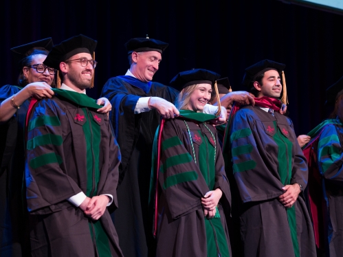 Faculty place doctoral hoods on several students at convocation
