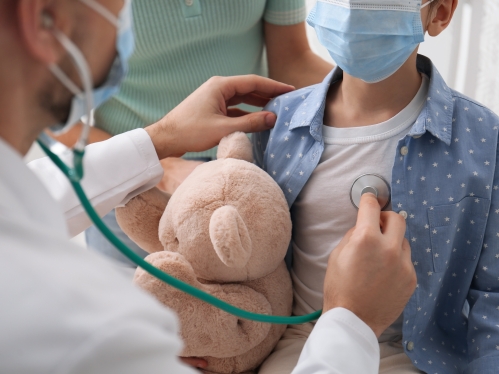 A pediatrician listens to a young patient's heart