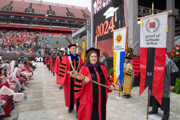 Secretary of the University Kimberlee M. Pastva holds the university mace as President Jonathan Holloway and dignitaries process onto the stage.